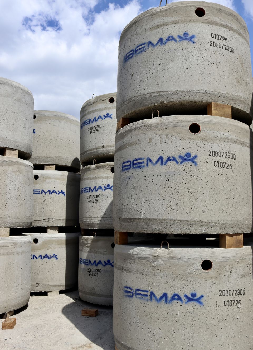 Gestapelde betonputten met het Bemax-logo op het stockplein in Alken